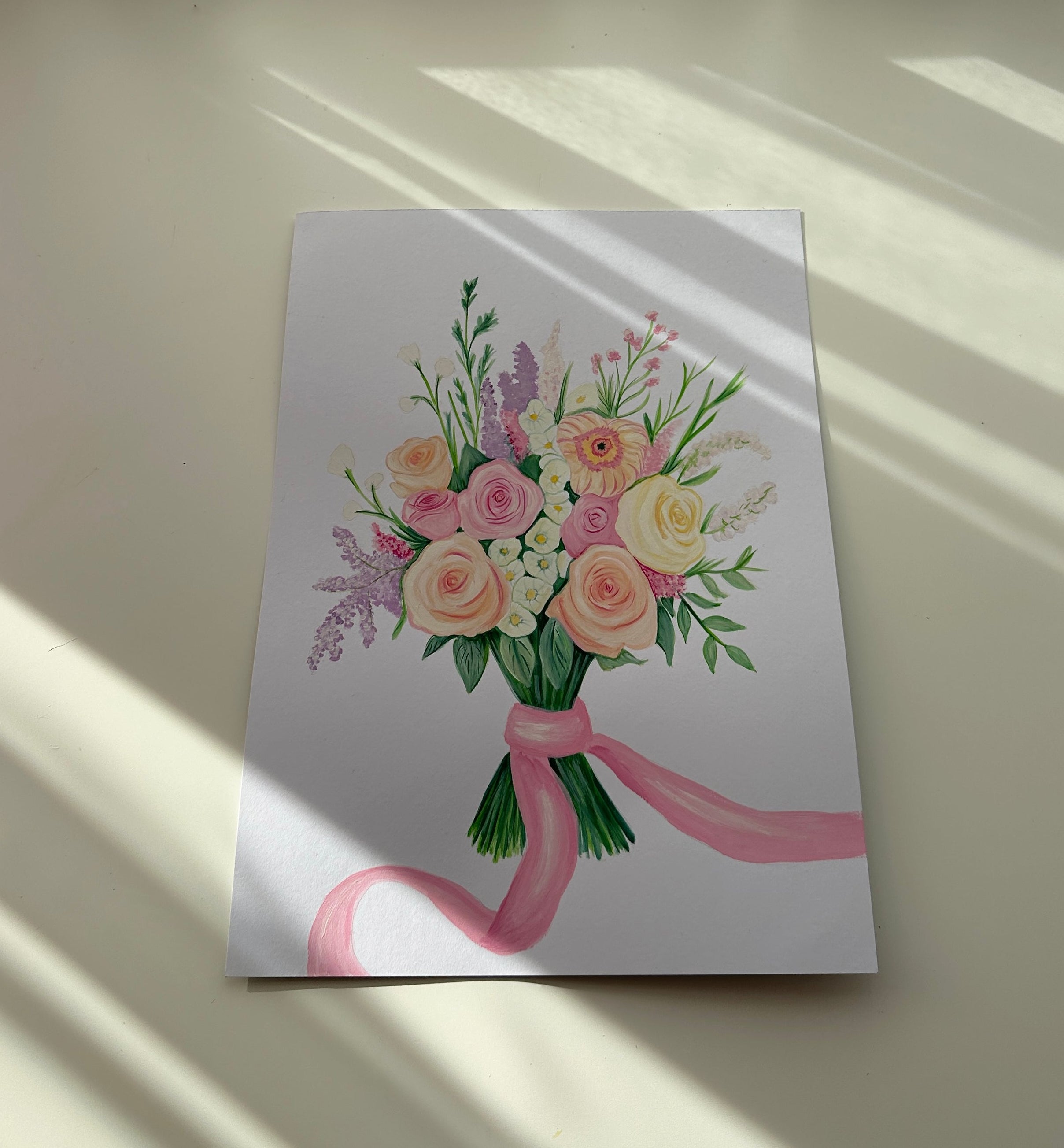 Small painting with floral design and pink ribbon on a white surface